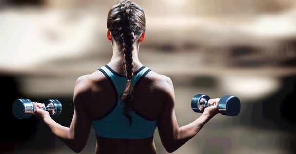 Composition of rear view of strong caucasian woman lifting dumbbells with copy space. sport, fitness and active lifestyle concept digitally generated image. - Φωτογραφία, εικόνα