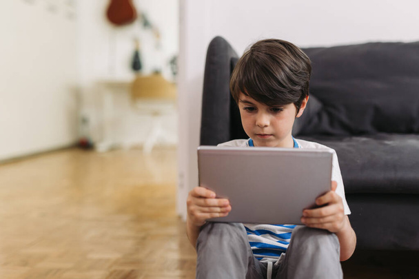 enfant utilisant une tablette numérique, assis sur le sol à la maison - Photo, image
