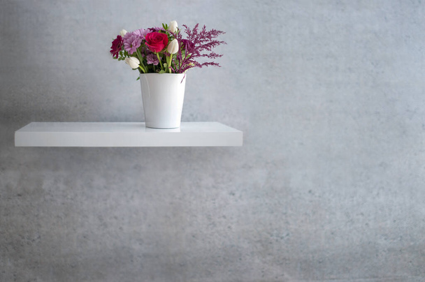 Spring flowers on floating white shelf against concrete wall design - Фото, зображення