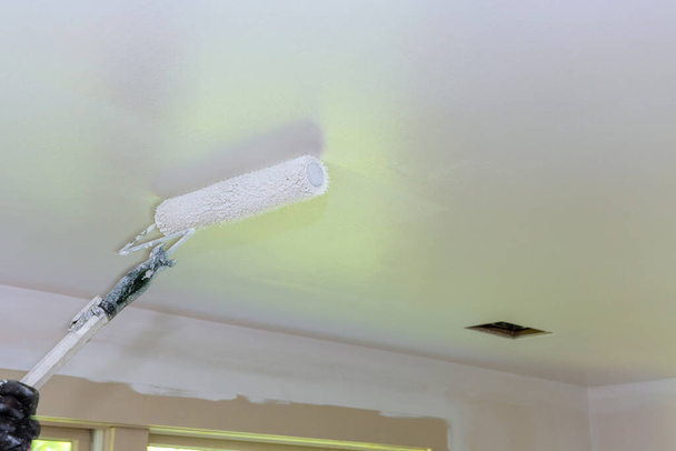 Home renovation in the of painter paints the ceiling with a roller in room - Foto, Imagem