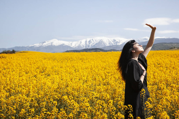 красивая девушка в черном платье, стоящая на поле - Фото, изображение