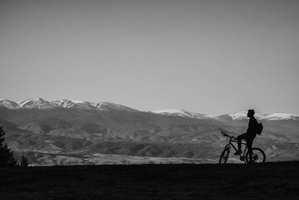 σιλουέτα του ανθρώπου ιππασία ποδήλατο σε φόντο βουνά  - Φωτογραφία, εικόνα