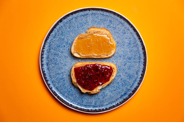 Мед, малинове варення та арахісове масло на білому тості яскраво-помаранчевий фон
 - Фото, зображення