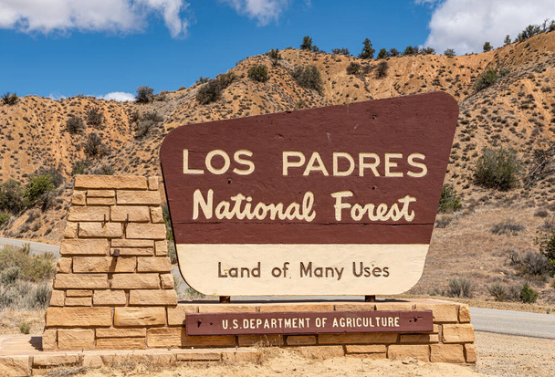 Los Padres Ulusal Ormanı, CA, ABD - 21 Mayıs 2021: Kahverengi tabelada Bej 'in önden yakın çekimi mavi bulutların altında parkın girişinde. Arka taraftaki sıradağ. - Fotoğraf, Görsel