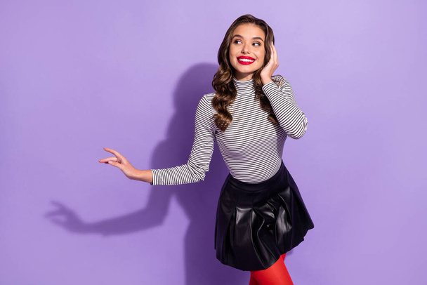 Photo of pretty shiny young lady dressed striped clothes looking pointing empty space dancing isolated purple color background - Photo, Image