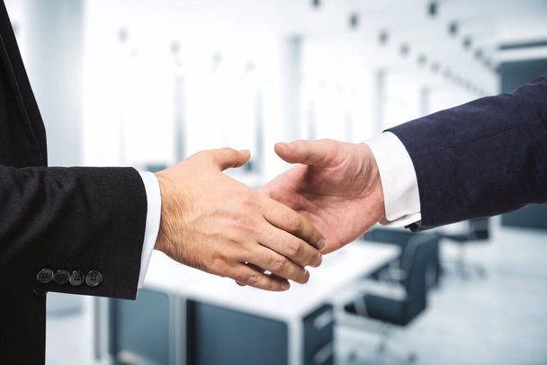 Two businessmen shake hands on the background of modern furnished office, partnership concept, close up - Фото, изображение