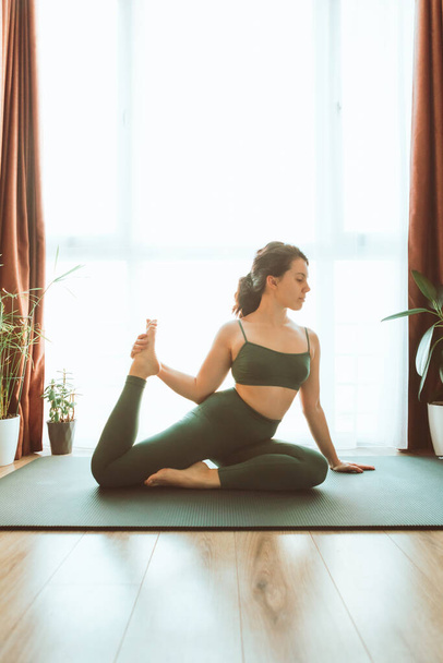 mujer hacer yoga en casa cerca de ventana grande estilo de vida saludable - Foto, Imagen