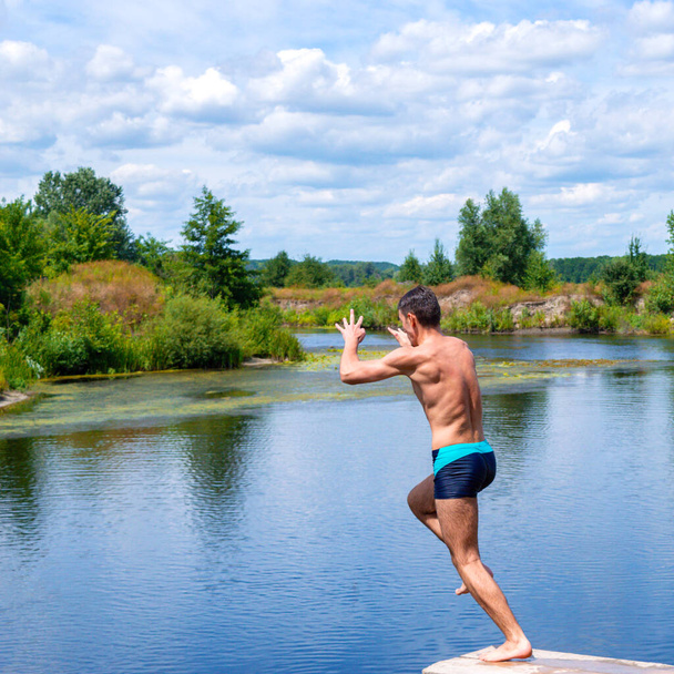 Urheilu teini hyppää jokeen aurinkoisena päivänä. Kaunis kesämaisema. Terveellisen elämäntavan käsite - Valokuva, kuva