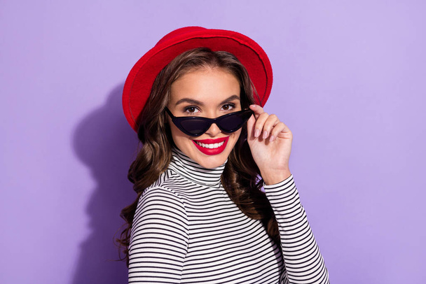 Photo of adorable sweet young woman wear striped outfit headwear arm dark eyewear isolated violet color background - Foto, Imagen