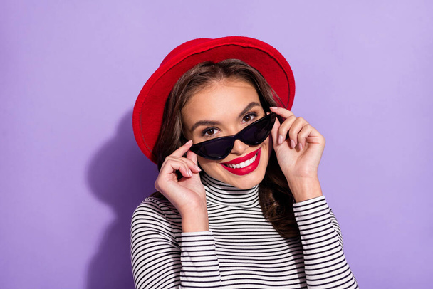 Photo of young attractive woman happy positive toothy smile hands touch sunglass isolated over purple color background - Photo, image