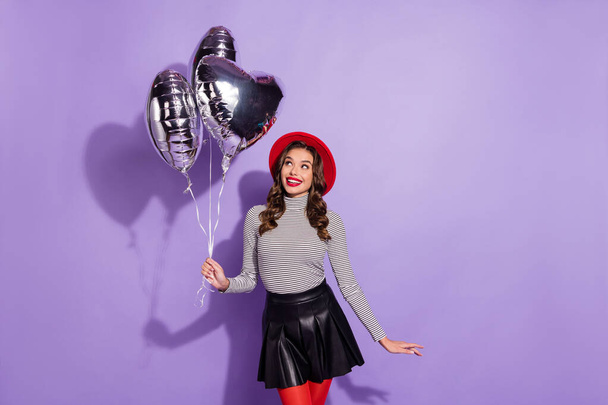 Photo of adorable satisfied lady toothy smile look arm hold balloons isolated on purple color background - Фото, изображение