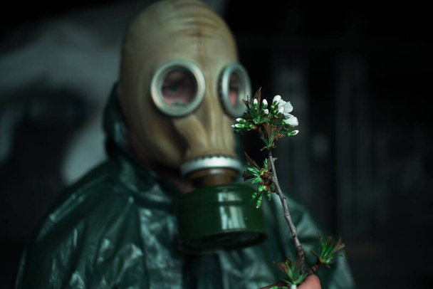 Scientist dosimetrist radiation supervisor in protective clothing and gas mask explores the danger zone. Close-up. Flower - Zdjęcie, obraz