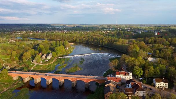Long Old Brick Bridge, Kuldiga, Latvia Across the Venta River. Captured From Above. The Widest Waterfall in Europe in Background - Photo, Image