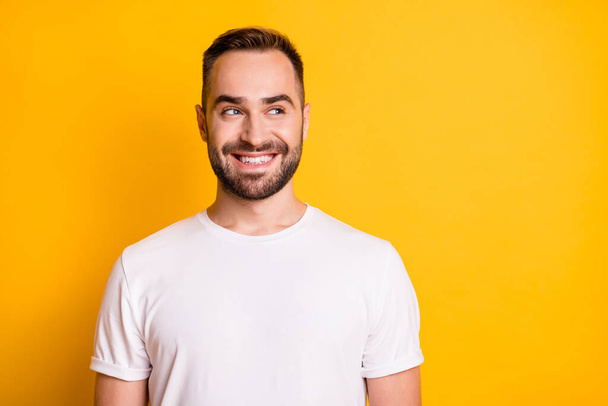 Portrait of optimistic guy look empty space wear white t-shirt isolated on vibrant yellow color background - Foto, afbeelding