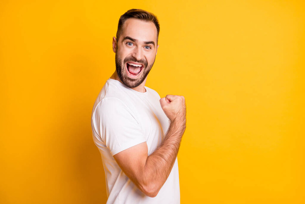 Profile portrait of optimistic guy hand fist yell wear white t-shirt isolated on vibrant yellow color background - Fotografie, Obrázek
