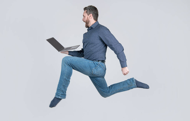 yllättynyt energinen hyppääminen mies liikemies käynnissä työskennellessään verkossa kannettavan tietokoneen kiire ostoksille, ostoksia. - Valokuva, kuva