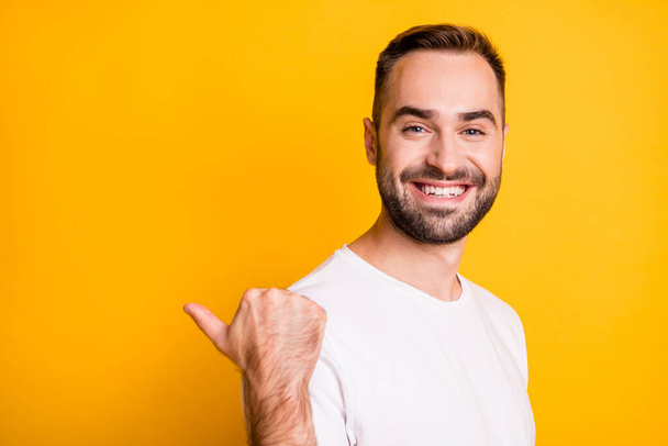 Profile portrait of optimistic cool guy point back empty space wear white t-shirt isolated on vibrant yellow color background - 写真・画像