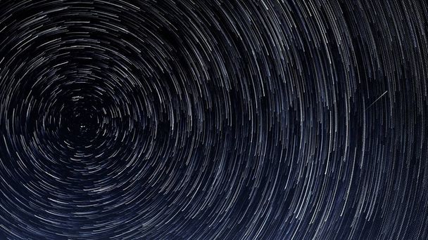 Hvězdné stezky, rotace jasných hvězd v noci kolem polární hvězdy proti modré obloze a meteoru - Fotografie, Obrázek