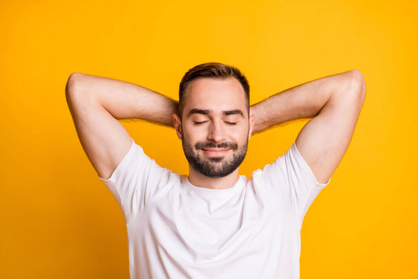 Portrait of optimistic guy lie down closed eyes wear white t-shirt isolated on vibrant yellow color background - Фото, изображение