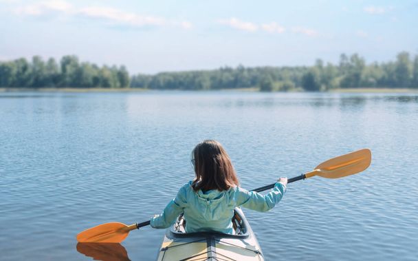 The woman is enjoying kayaking. Purity and silence of Nature. Calm water. - 写真・画像