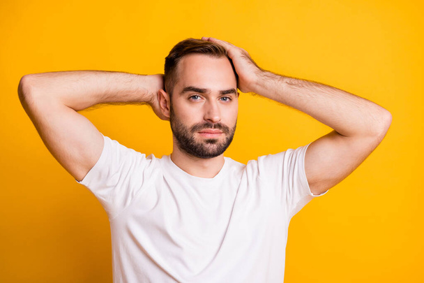 Portrait of attractive well-groomed guy caressing healthy hair isolated over bright yellow color background - Foto, Imagem