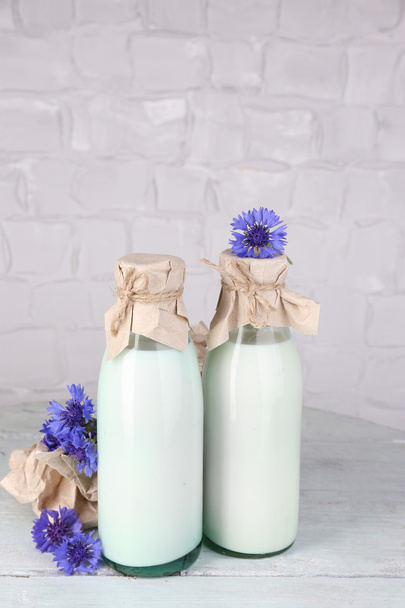 Bottles of milk and cornflowers on wooden table - Foto, afbeelding