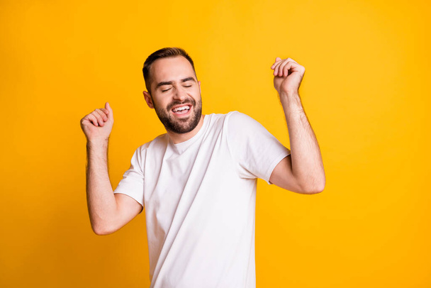 Portrait of optimistic guy dance sing wear grey t-shirt isolated on yellow color background - Foto, afbeelding