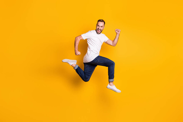 Full length body size photo of jumping cheerful male model wearing stylish outfit isolated vivid yellow color background - Foto, Bild
