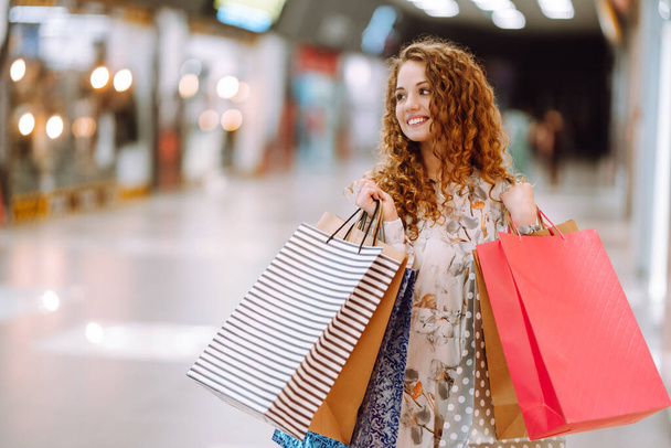 Fashionable woman with multi-colored bags in modern shop center.  The joy of consumption. Consumerism, sale, purchases, shopping, lifestyle concept. - Photo, image