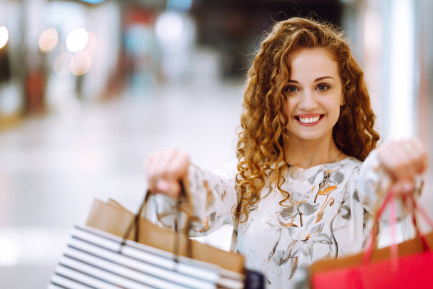 Mujer de moda con bolsas multicolores en el centro de la tienda moderna. La alegría del consumo. Consumismo, venta, compras, compras, concepto de estilo de vida. - Foto, imagen