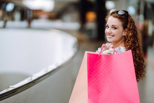 Fashionable woman with multi-colored bags in modern shop center.  The joy of consumption. Consumerism, sale, purchases, shopping, lifestyle concept. - Фото, зображення