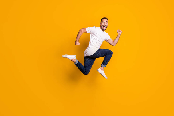 Full length body size side profile photo of jumping man running fast isolated vibrant yellow color background - Φωτογραφία, εικόνα