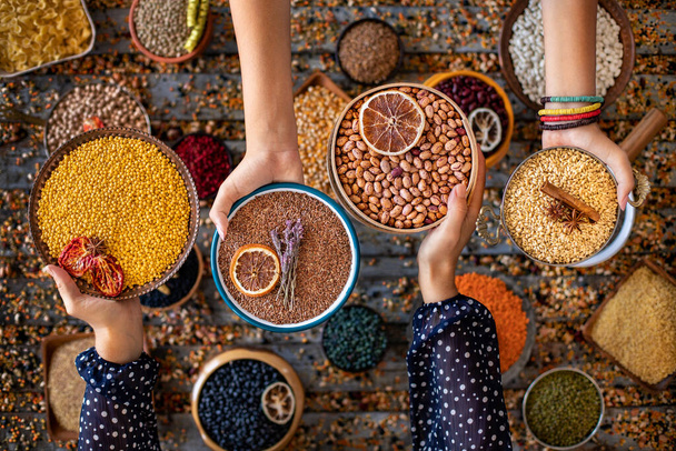 Various of beans at the hands of two women in the bowl - Photo, Image