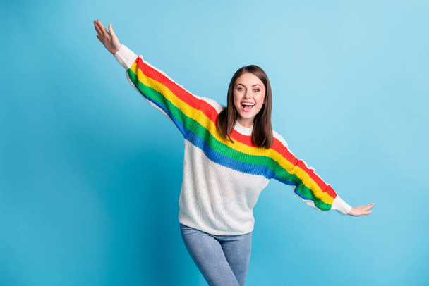 Photo of charming childish young lady wear colorful pullover smiling arms sides isolated blue color background - Foto, Imagem