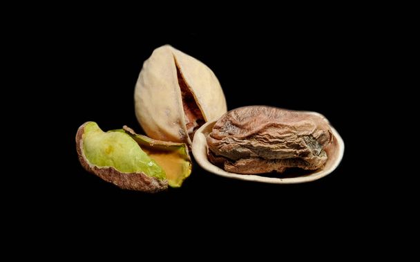 peeled pistachio nuts and with peels, photographed by macro photography on a black background - Fotografie, Obrázek