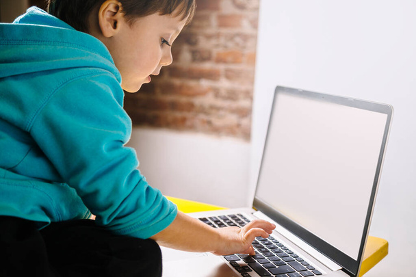Petit garçon regardant avec étonnement à un ordinateur portable. - Photo, image