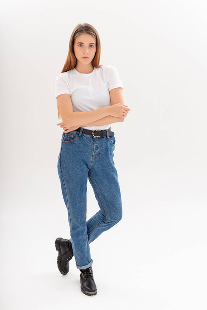 jovem caucasiano menina bonita com cabelos longos em t-shirt, jeans azuis no estúdio - Foto, Imagem