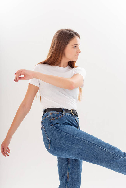 young caucasian pretty girl with long hair in t-shirt, blue jeans at studio - Foto, imagen