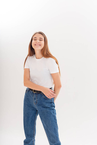 young caucasian pretty girl with long hair in t-shirt, blue jeans at studio - Фото, зображення