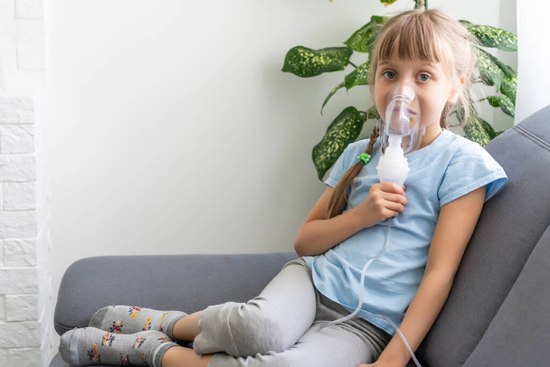 自宅でネブライザーで吸入する少女。子供喘息吸入ネブライザー蒸気病気咳の概念. - 写真・画像