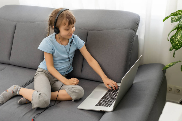 Вид ззаду молода дівчина сидить вдома, розмовляє з учителем або викладачем онлайн, школярка-підліток, яка займається веб-розмовою, вивчає програму дистанційного використання веб-конференції на ноутбуці
 - Фото, зображення
