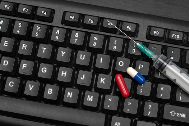 Pills and syringe on computer keyboard. Darknet drug trade concept - Photo, Image