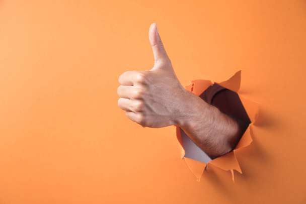 Рука показывает большой палец вверх на оранжевом фоне - Фото, изображение