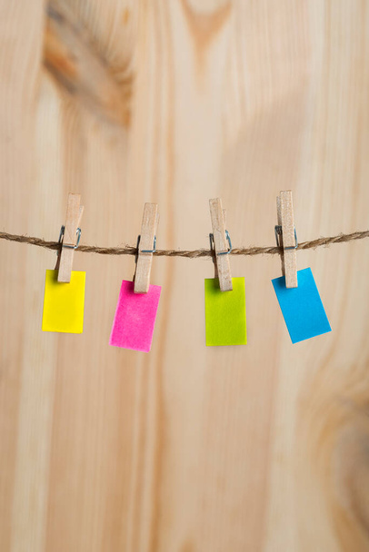 Multicolored paper notes hang with clothespins on rope. Copy space. Place for your text. Vertical frame. - Photo, image