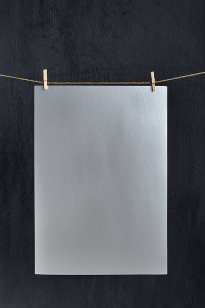 Gray paper sheet hanging with clothespins on rope. Place for your text. Copy space, mockup. Vertical frame. - Foto, Bild
