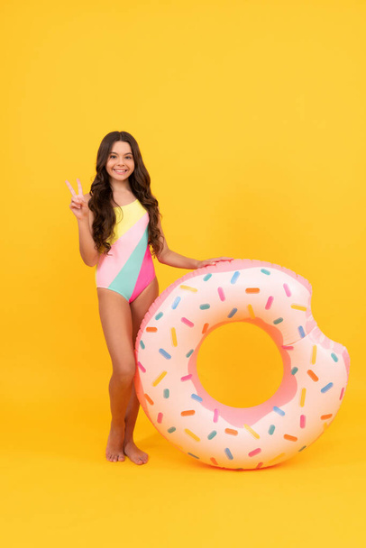 kid in swimming suit with doughnut inflatable ring on yellow background, summer vacation. - Fotoğraf, Görsel