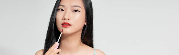 Atraktivní a krásné asijské dívka namalovat rty růžová rtěnka, usmívající se make-up dívka izolované na bílém pozadí - Fotografie, Obrázek