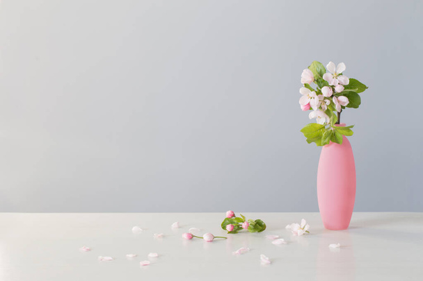 branches of  apple tree with flowers in pink vase on white table - Fotografie, Obrázek