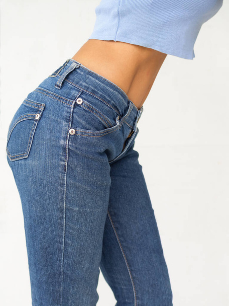 Slim woman with jeans on white background. Shapely girl young waist standing close up. authentic skin tan and sexy fit body. for Lose weight, diet and healthy lifestyle concept. - Zdjęcie, obraz
