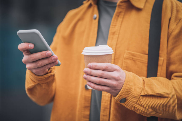 Man in an orange jacket with a phone in his hands - Fotoğraf, Görsel